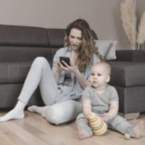 Mother on phone with toddler near by Single Mama Way